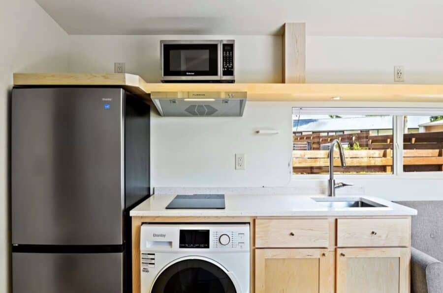 Compact tiny house kitchen with modern appliances and natural light.
