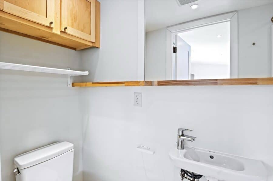 Compact tiny house bathroom with sink and mirror in ESCAPE Villa Duplex.