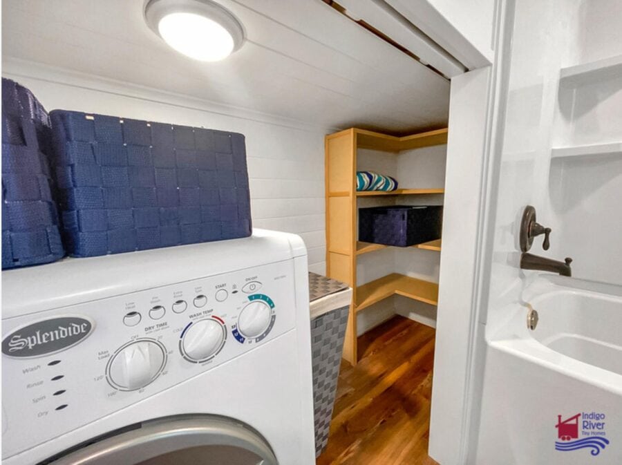 Compact laundry space in a tiny house with washer and shelving.