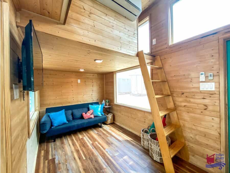 Cozy tiny house living room featuring wooden walls and a blue sofa.