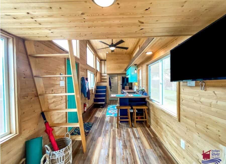 Cozy tiny house interior featuring wooden walls, large windows, and compact living space on land.