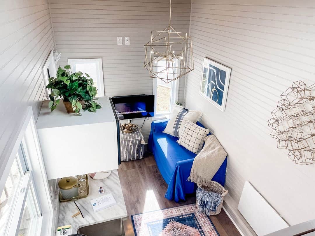 Small cozy living room in a tiny house with blue sofa and modern decor.