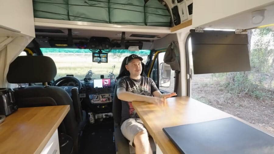 Compact van life interior with custom furnishings inside a T1N Sprinter chassis.