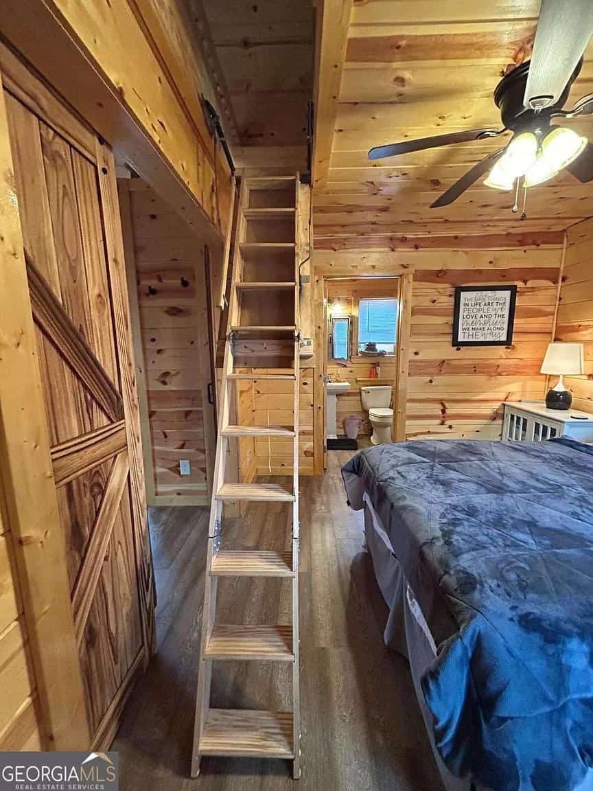 Charming tiny house bedroom featuring a ladder leading to a cozy loft space among natural wood inter.