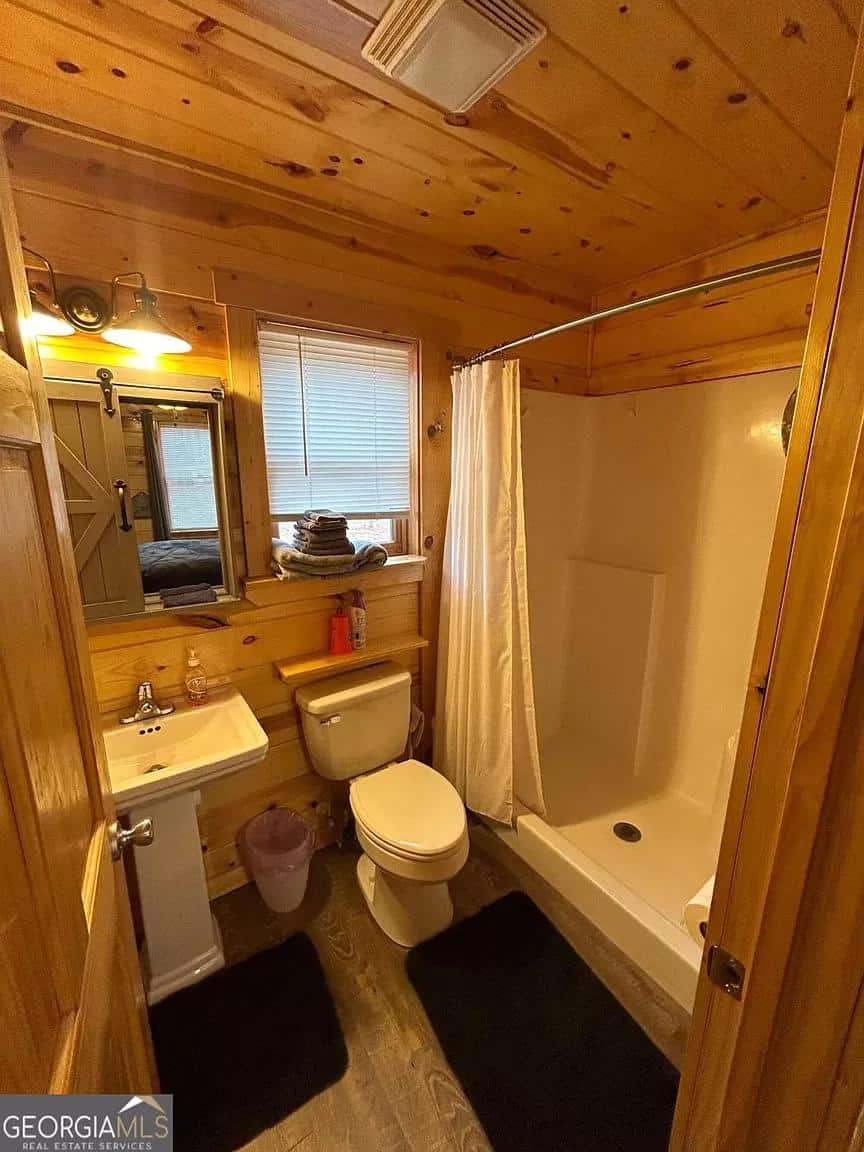 Small cabin bathroom featuring a compact shower, toilet, and wooden accents. Perfect for rustic tiny.