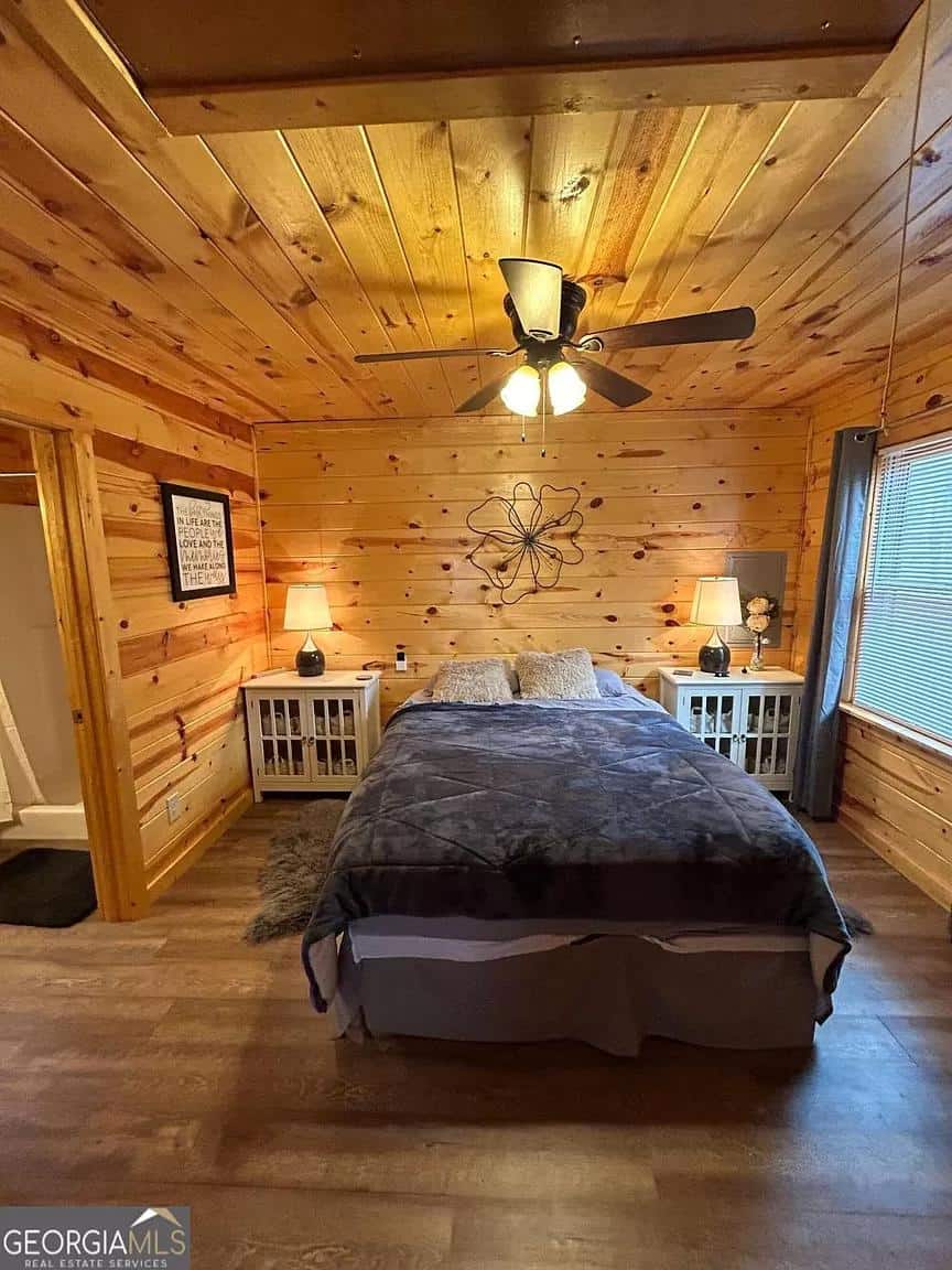 Charming bedroom in a whispering hills cabin featuring wood-paneled walls and ceiling, a comfortable.
