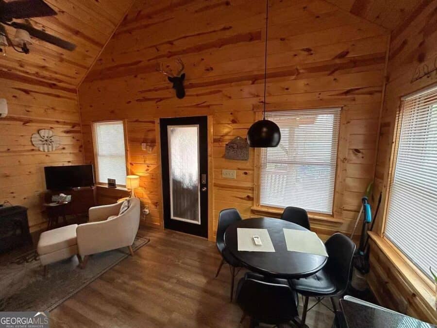 Charming tiny house interior with wooden walls, cozy seating, and a dining area amid nature.