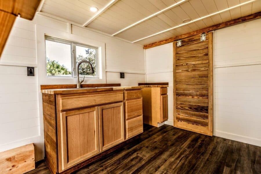 Compact tiny house kitchen with wooden cabinetry and modern fixtures.