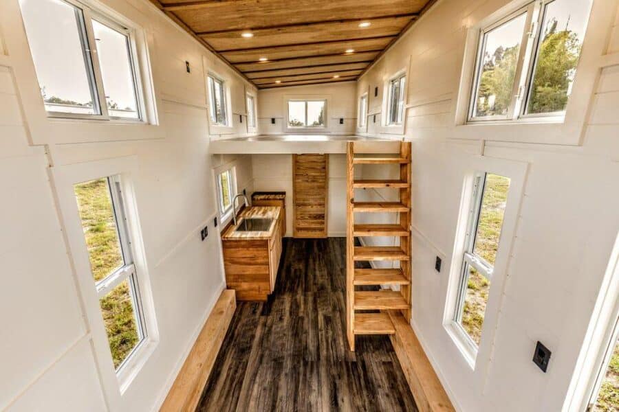 Interior view of a tiny house with wooden stairs, natural light, and compact design in Florida.