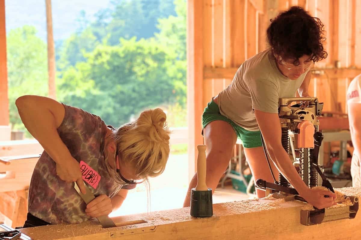 Student using hand tools and chisel during the timber framing workshop at Wild Abundance
