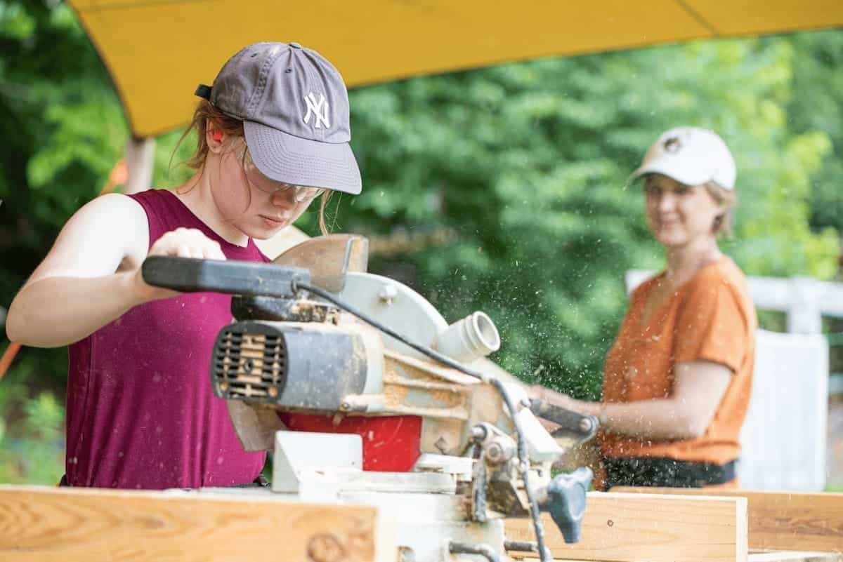 Two women learning to use a miter saw at the Wild Abundance carpentry class