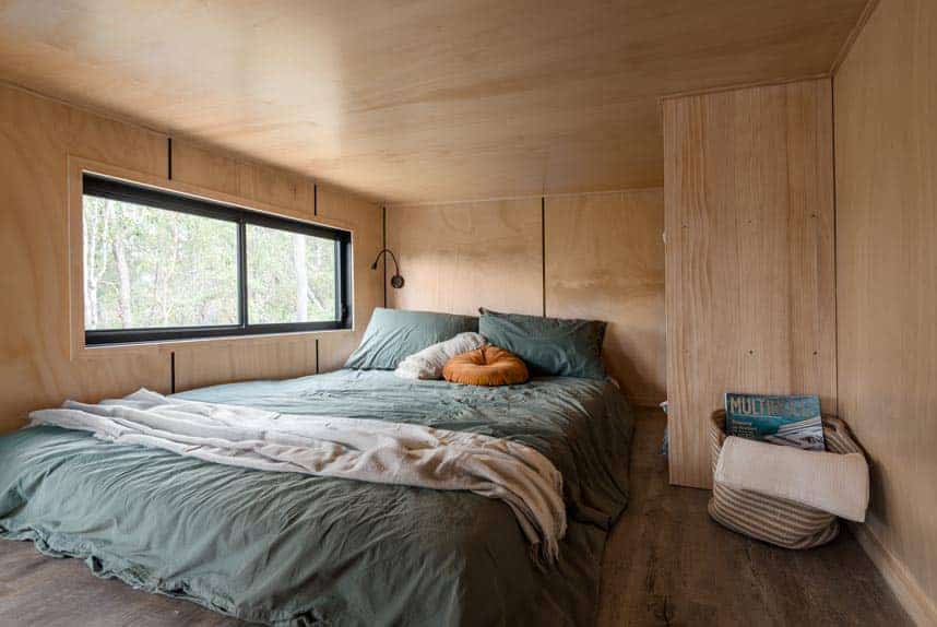 Ground-floor main bedroom beneath the living platform in the Wildscape tiny house