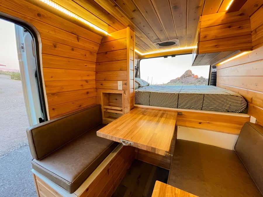 Compact camper van interior with wooden accents and built-in seating.