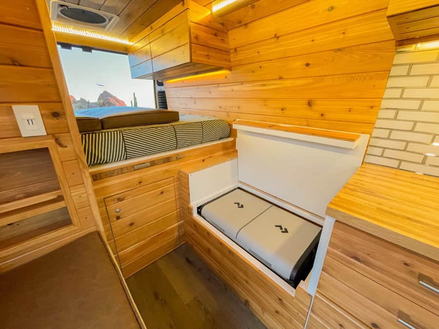 Compact camper van interior with wooden accents and built-in sleeping area.