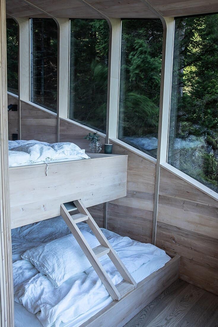 Bunk-style sleeping arrangement inside the Woodnest Original treehouse with glass wall and forest view