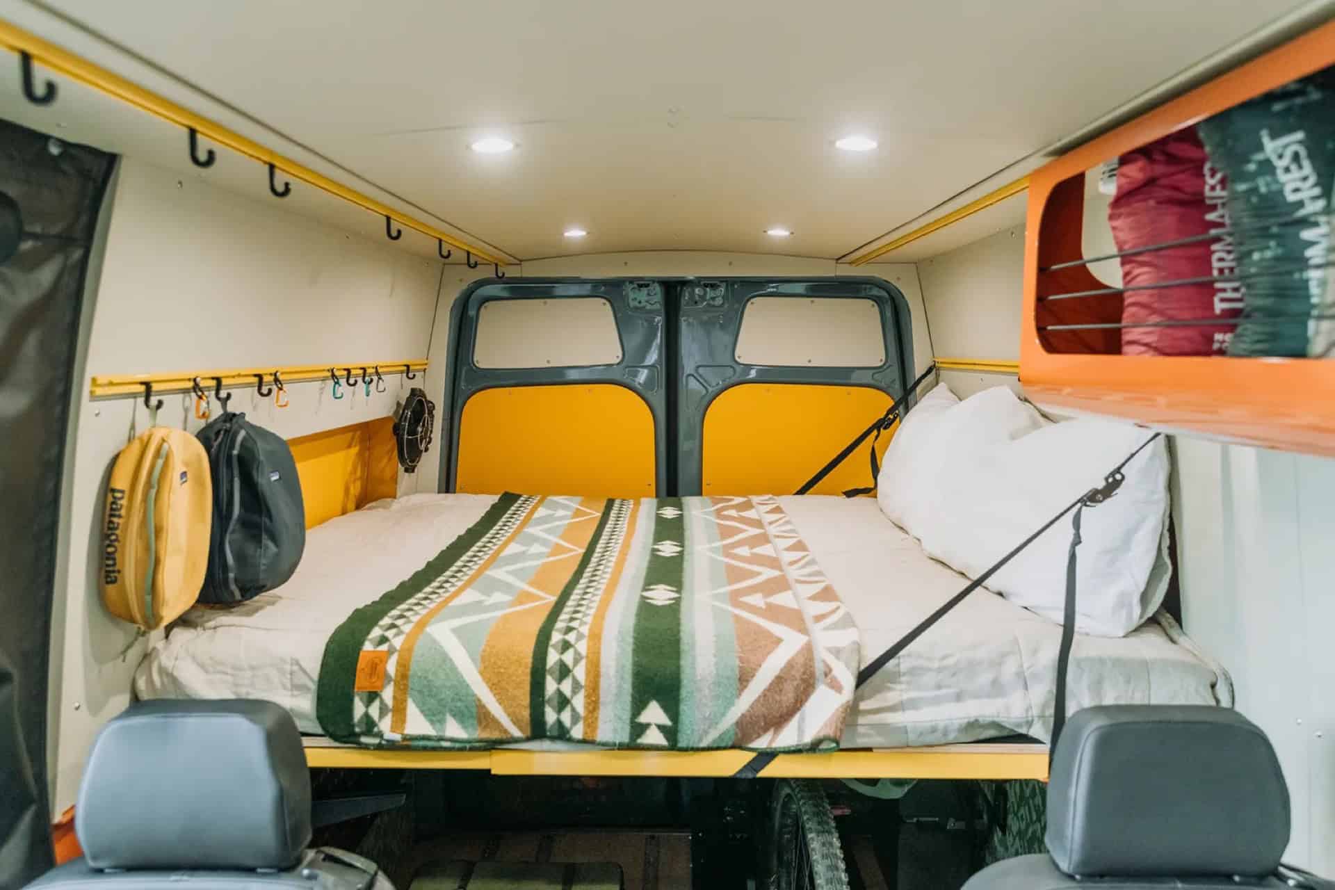 Murphy bed folded down across the back of GB01 with a patterned wool blanket and gear hanging on the walls