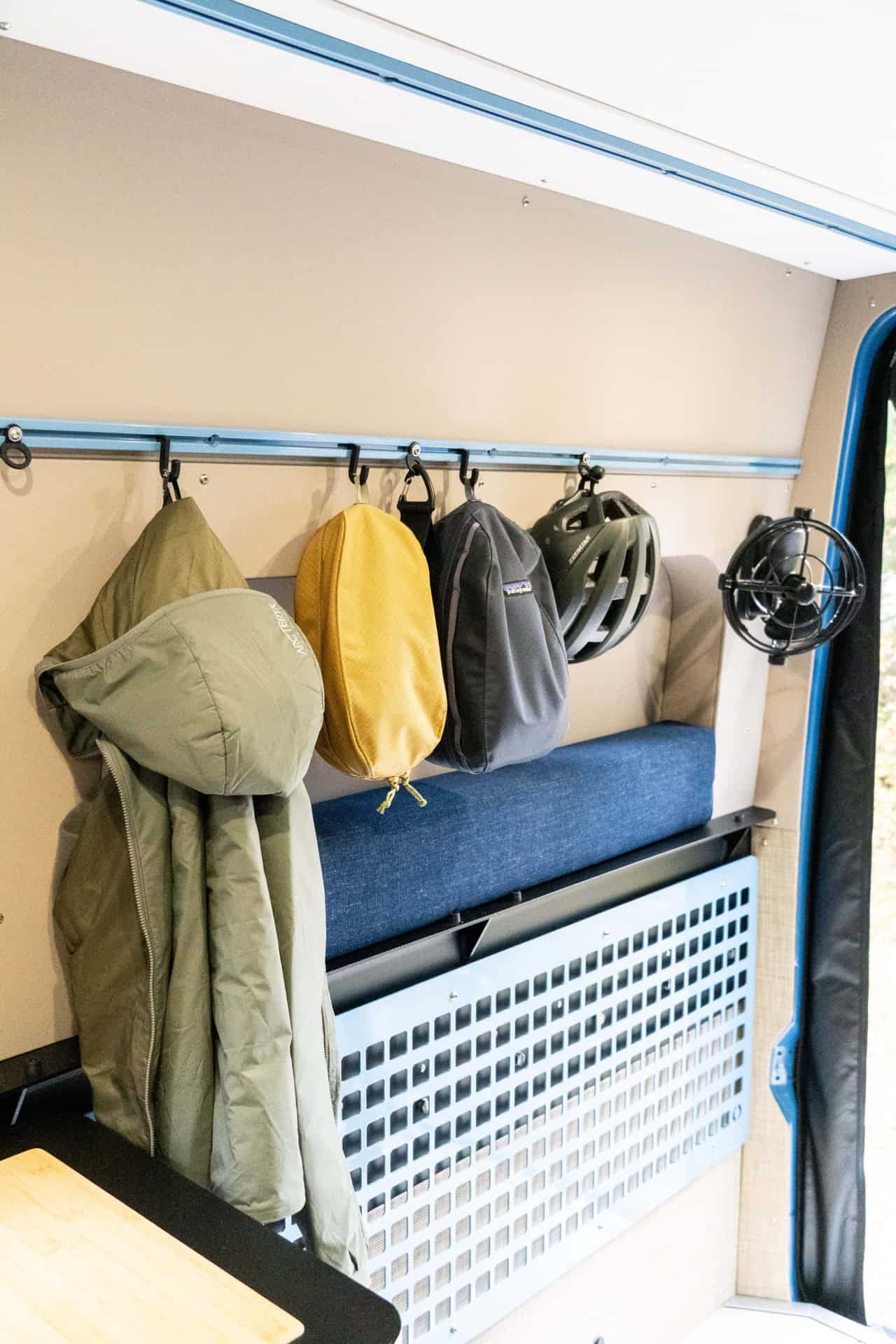 Peyto bench seat with a hanging rail above holding a jacket, bags, a helmet, and a fan