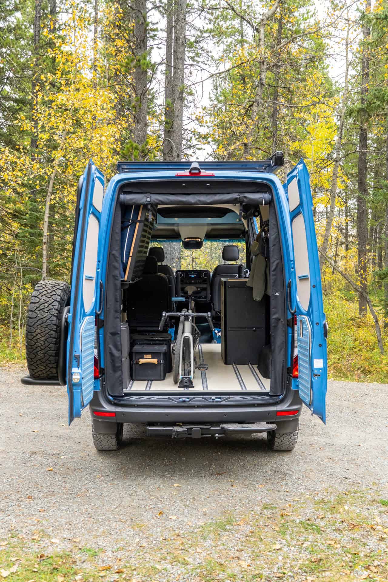 Rear doors of the Peyto camper van open, showing a bicycle stored inside the cabin