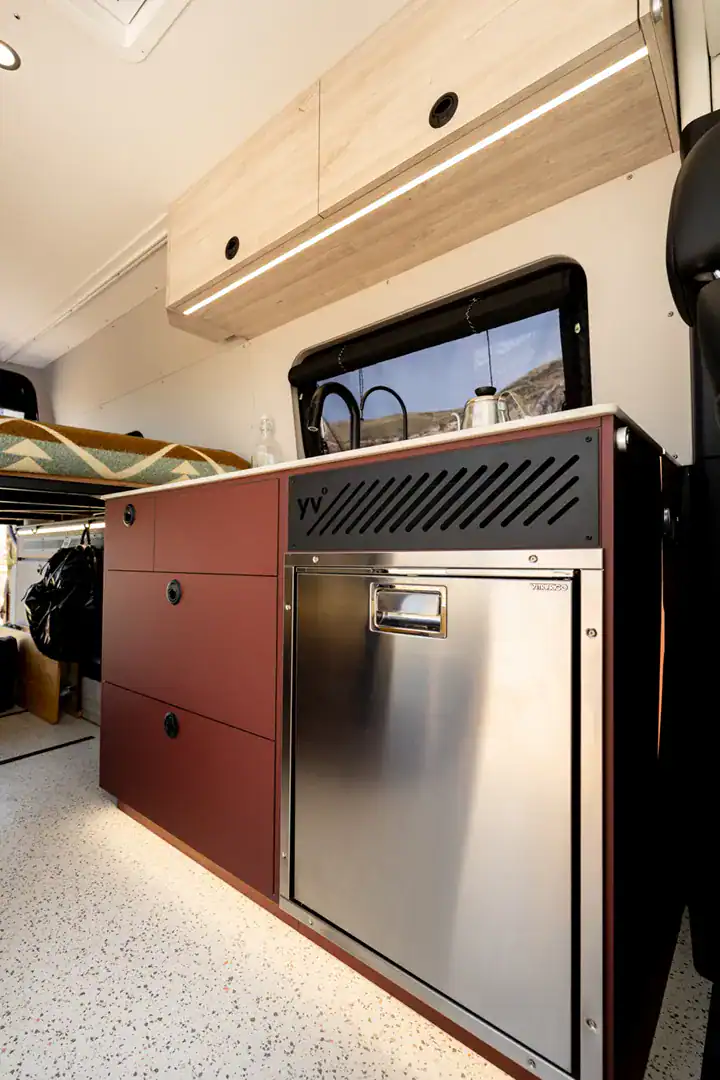 A stainless compressor refrigerator built into the terracotta and maple cabinetry of the Yama Vans Brio