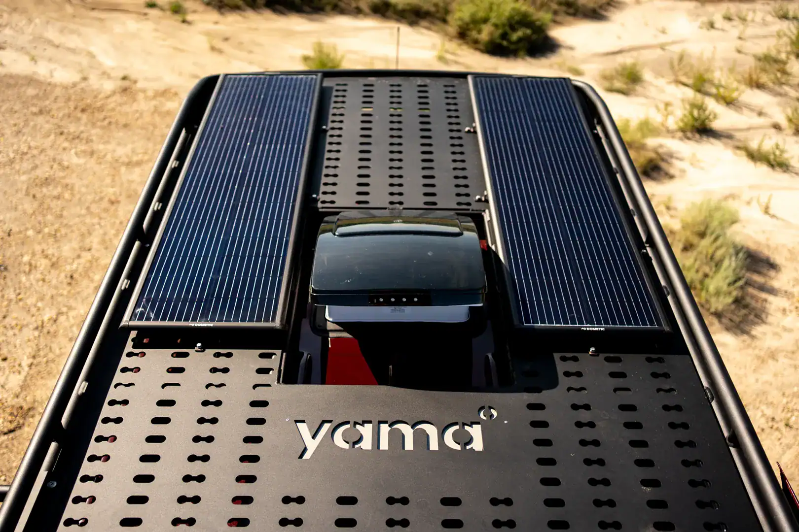 The roof of the Yama Vans Brio with two solar panels, a roof fan, and a Yama-branded rack