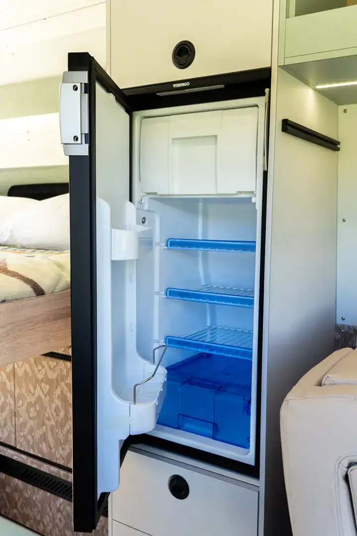 An upright compressor refrigerator built into the cabinetry of the Yama Vans Fitz