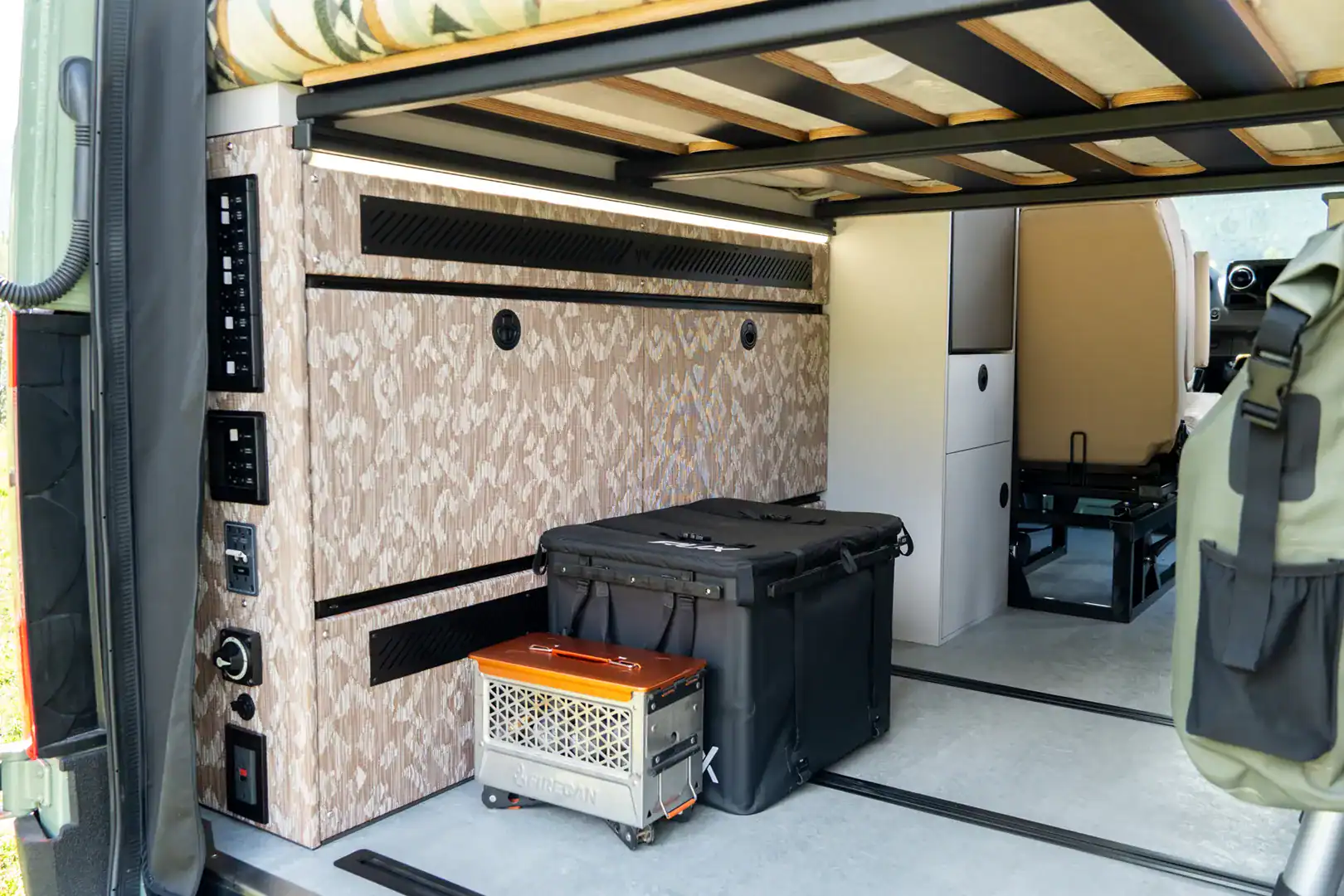 The patterned gear garage beneath the bed of the Yama Vans Fitz with storage boxes and control panels