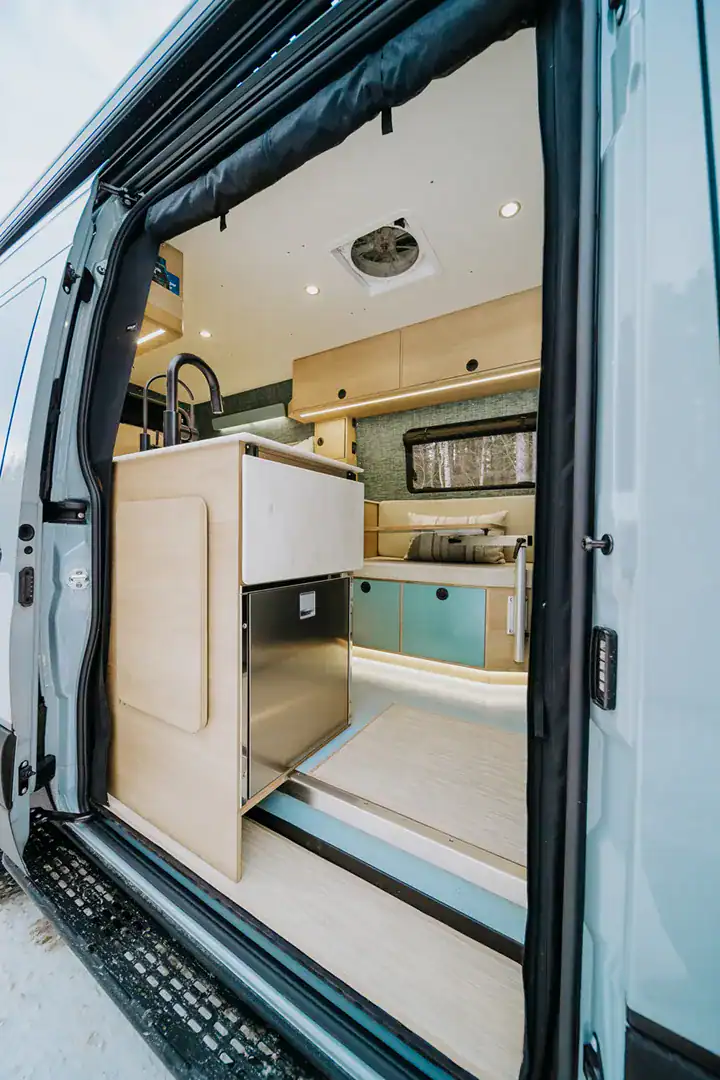 The galley of the Yama Vans Furō with a sink, cooktop, and maple cabinetry