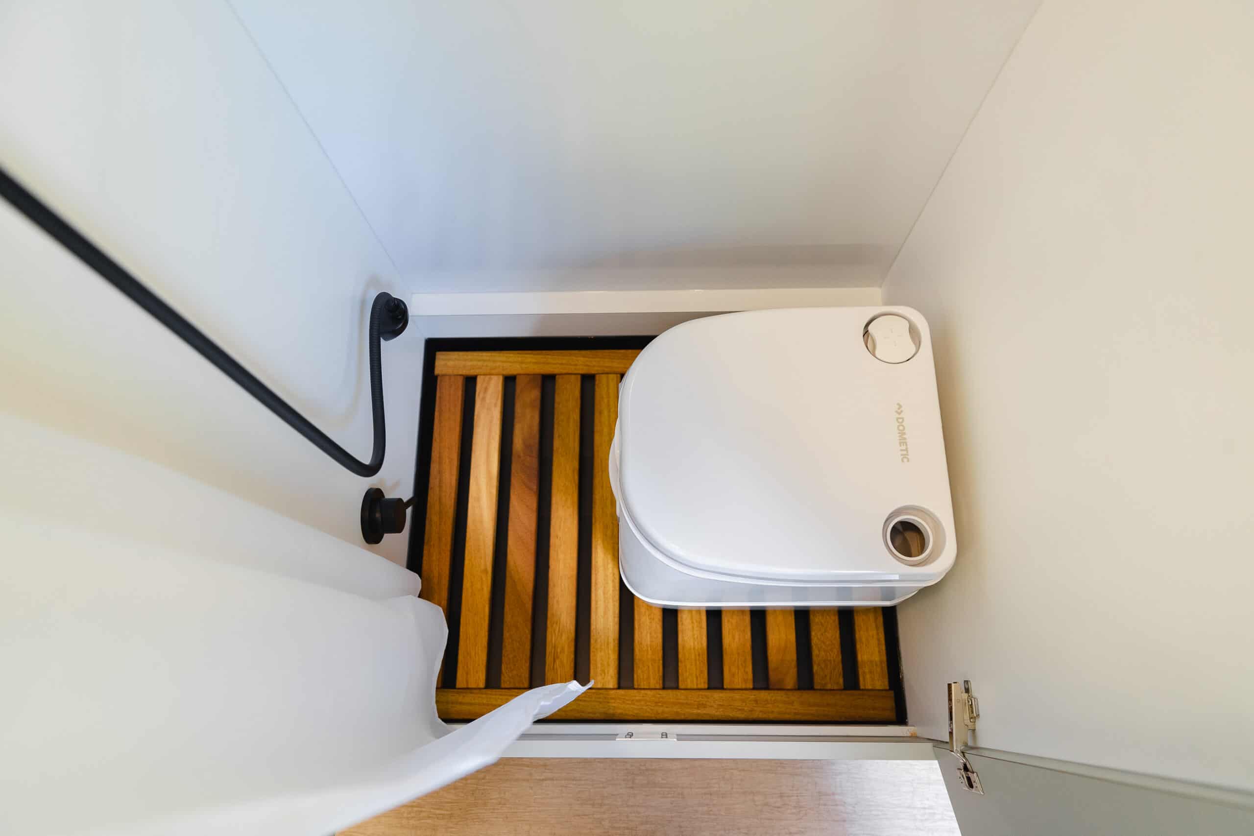 A cassette toilet on a teak floor inside the full-height wetroom of the Yama Vans Gatsby