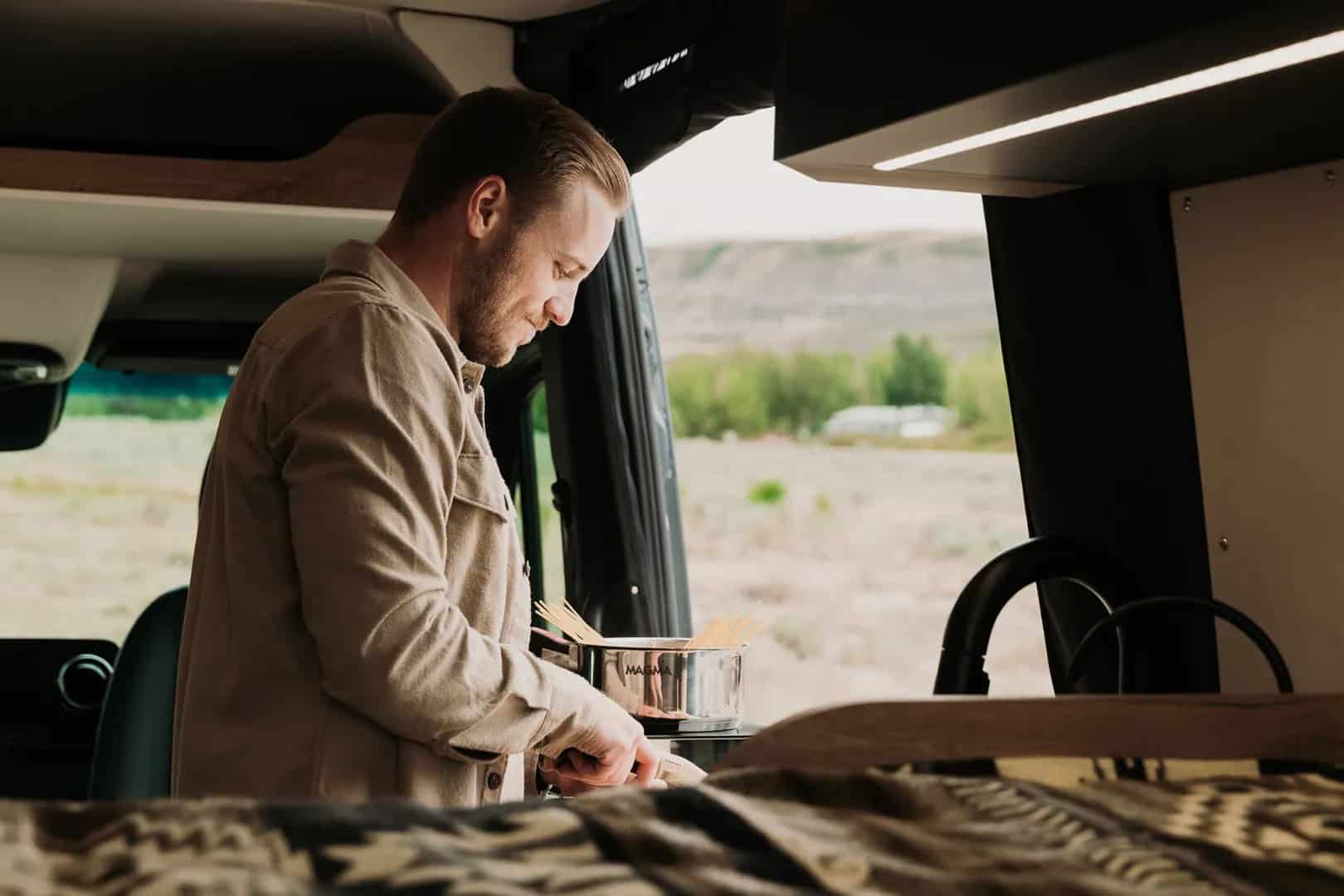 Person cooking at the galley kitchen of a Yama Vans Teton 01N with the sliding door open