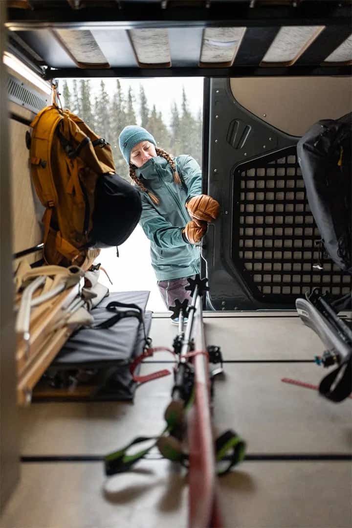 Skis, packs, and a helmet organized on MOLLE panels inside the Yama Vans Teton 01N gear garage