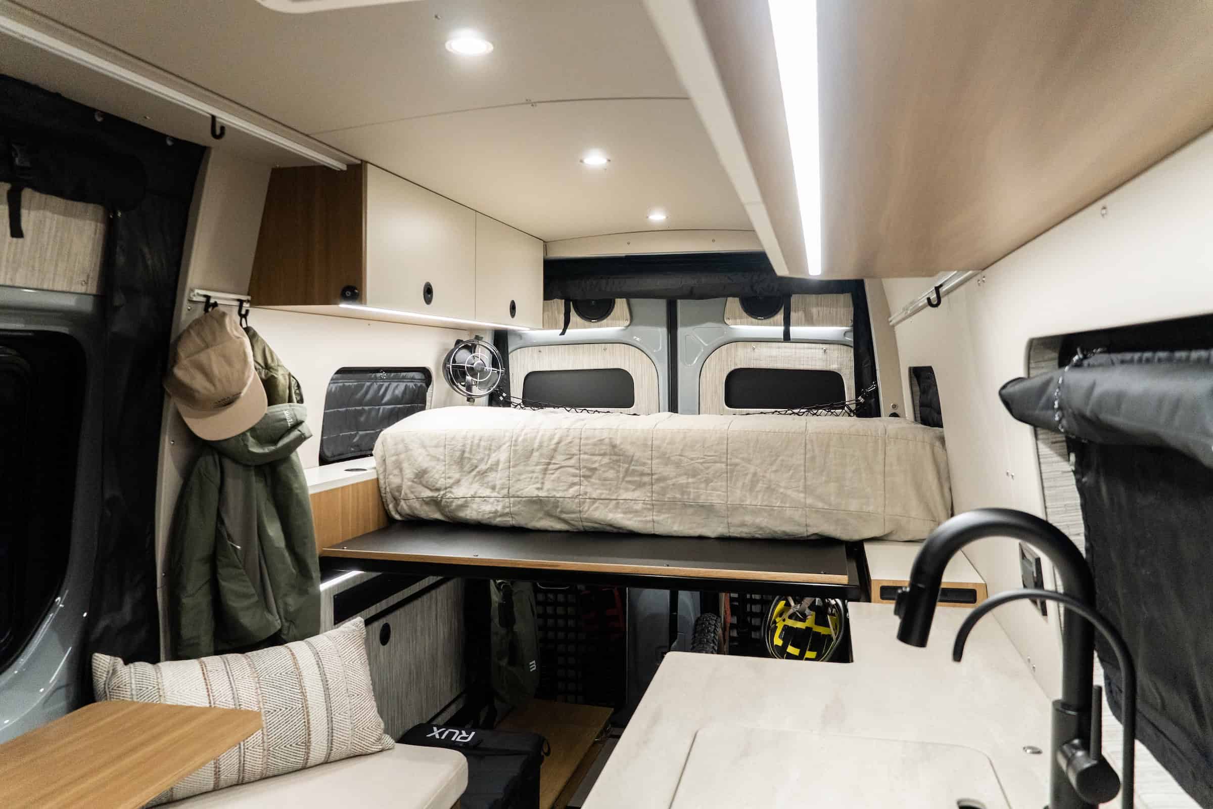 The living and dinette area of the Yama Vans Trekka with bench seating, the bed behind, and the gear garage below