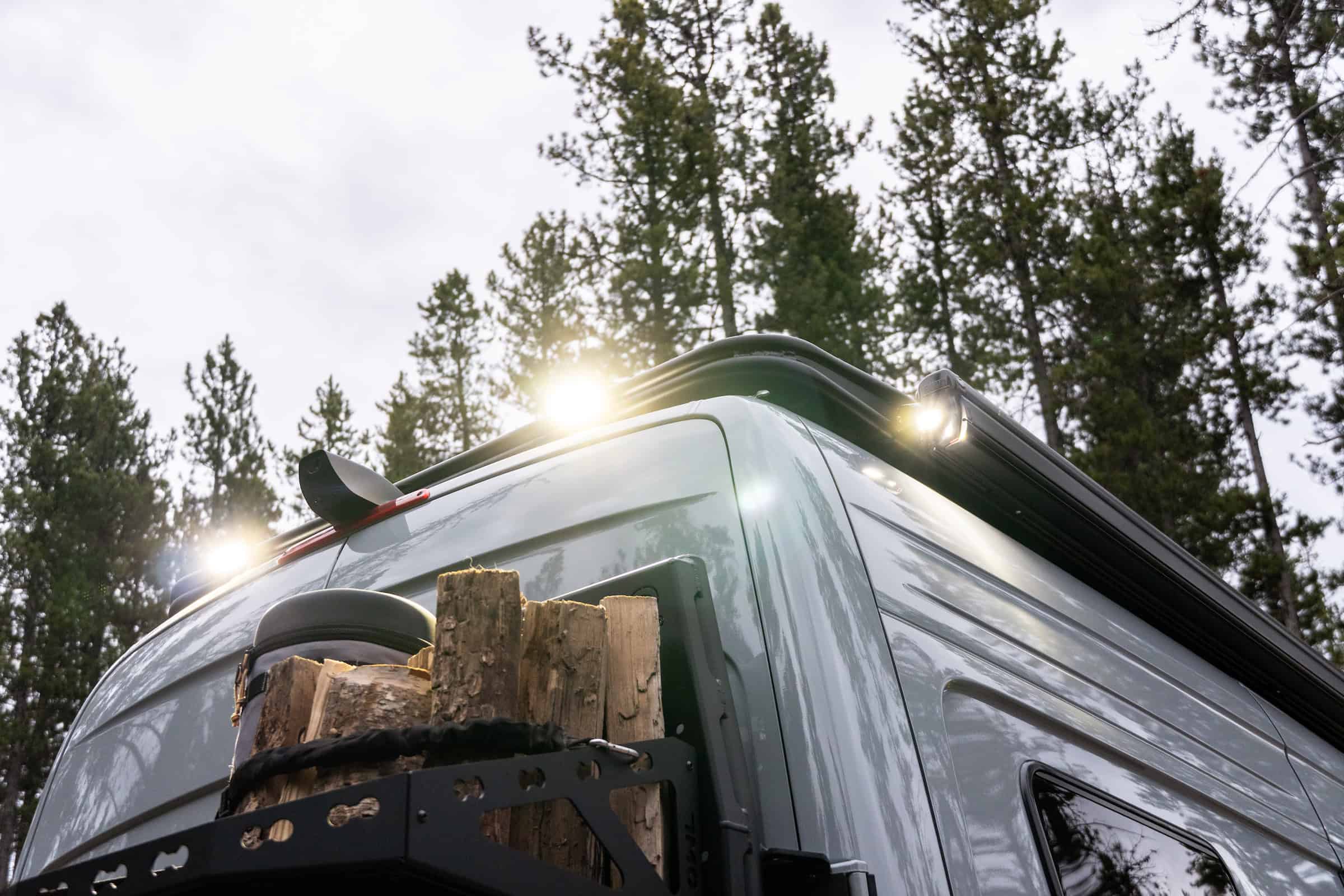 The roof of the Yama Vans Trekka with off-road lighting and a rack carrying firewood at dusk