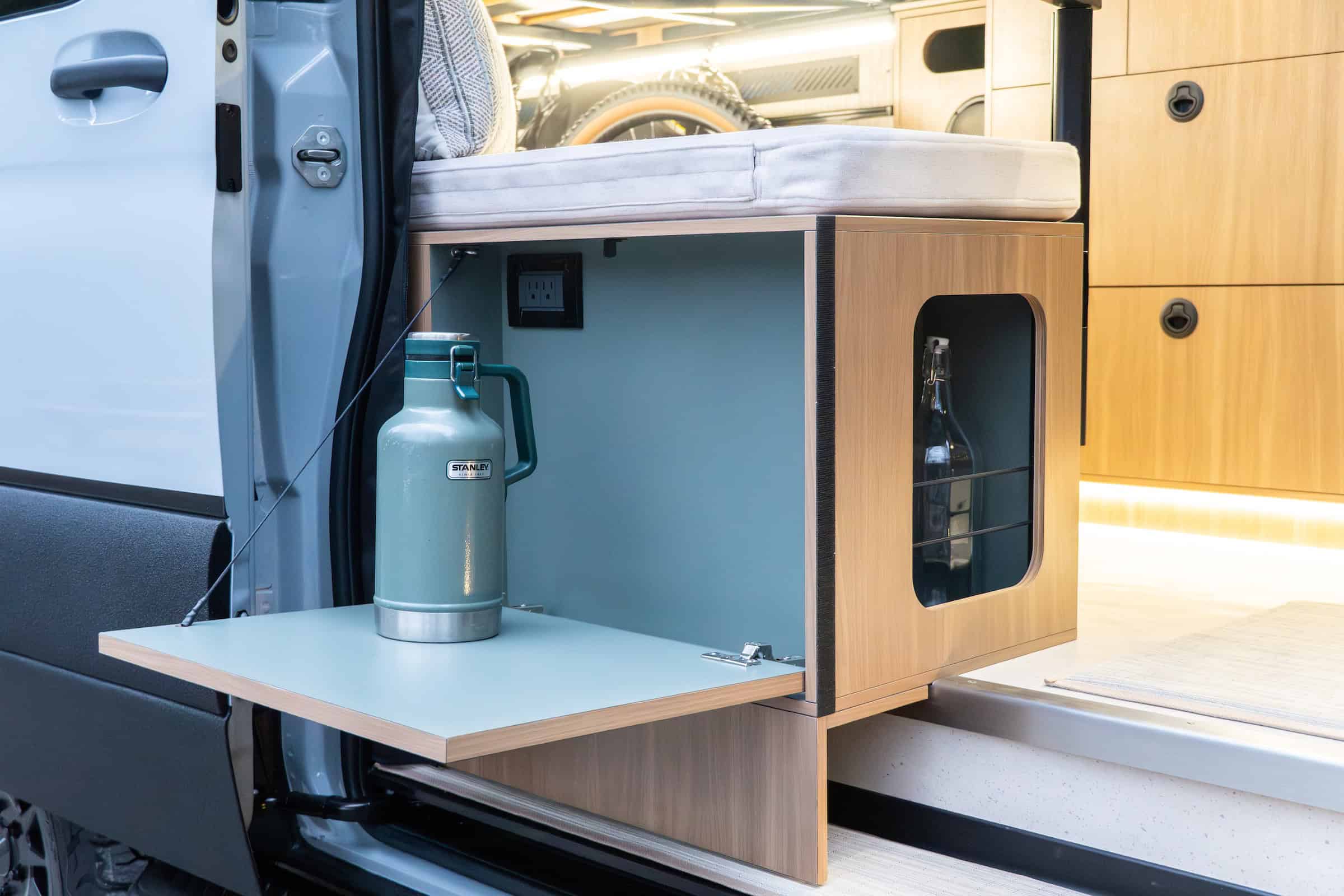 A swing-out exterior prep shelf and slide-out cabinet on the side of the Yama Vans Trekka