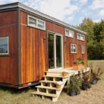 Charming tiny house with wooden exterior and multiple windows, perfect for minimalist living.