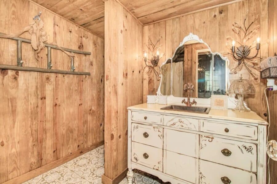 Bathroom in Little Farm Cottage with rustic wooden walls and vintage decor.