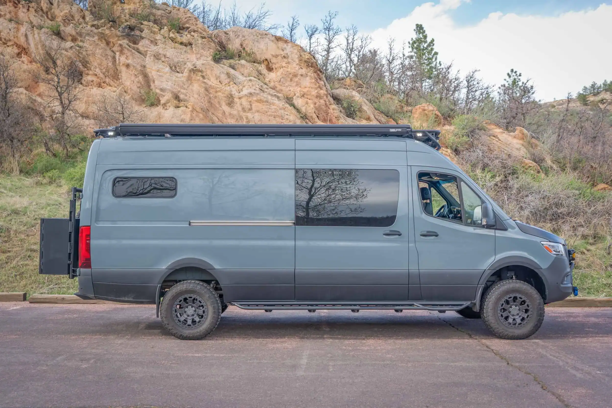 Modern gray camper van with rooftop storage, ideal for tiny house living and adventures.