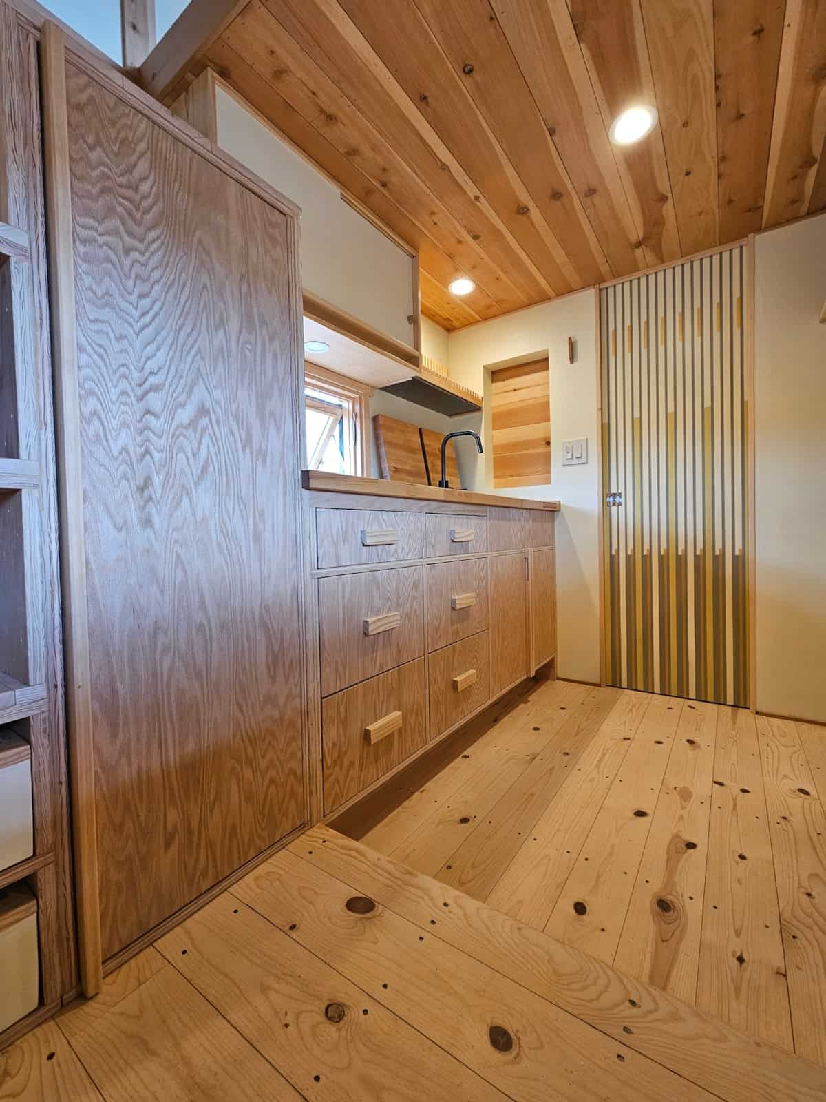 Kitchen galley with birch counters, custom wood drawers, built-in dish rack, and spruce plank floors