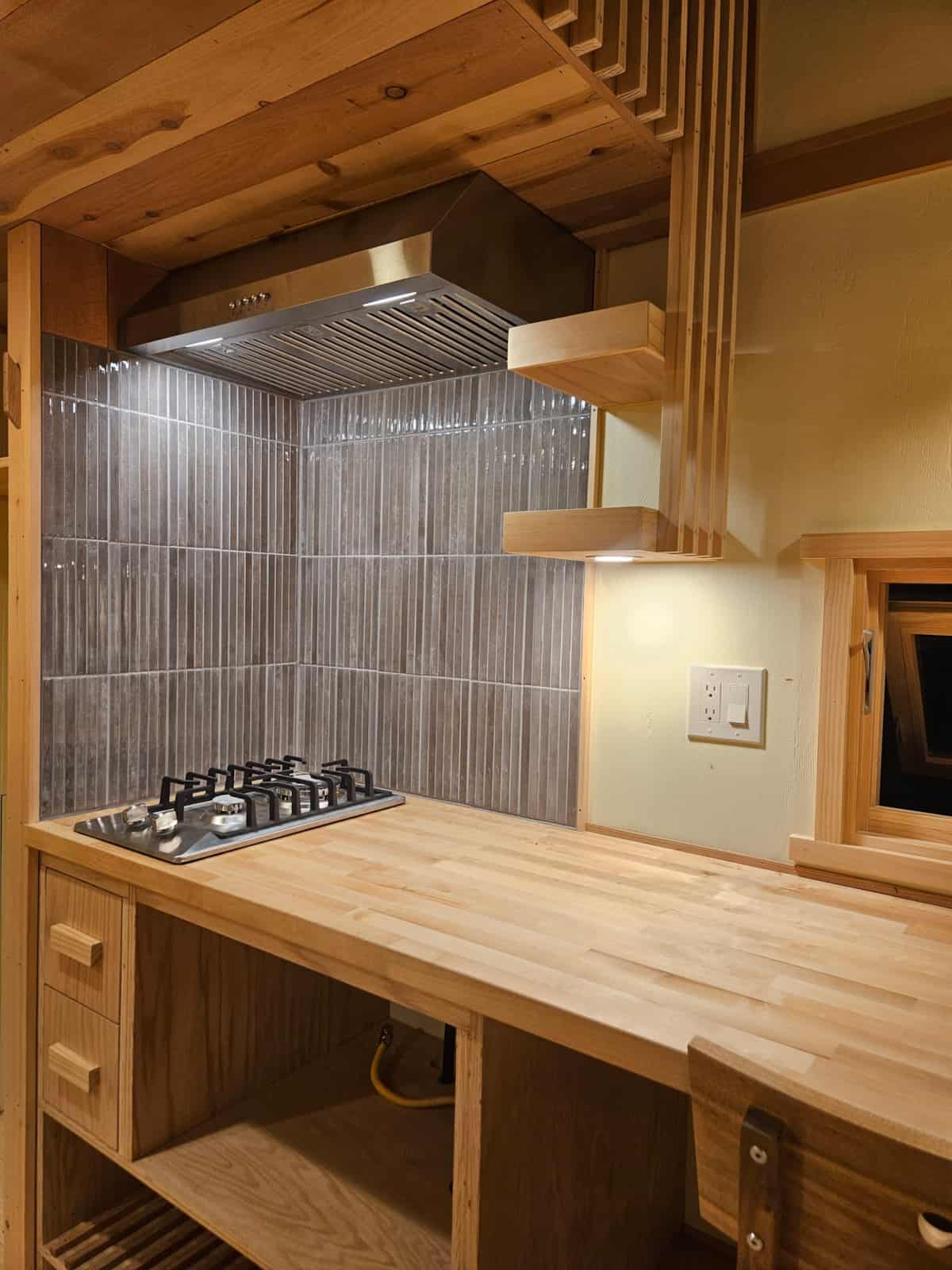 Two-burner LP gas range set into a birch butcher-block counter with a vertical grey tile backsplash