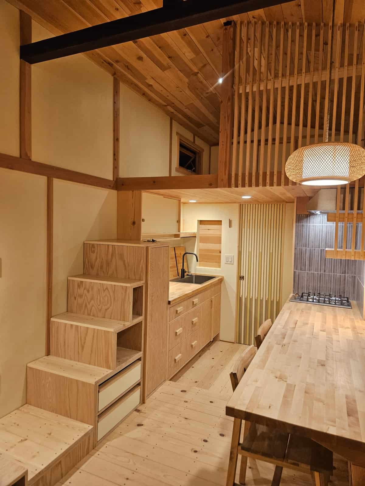 Tansu-style storage stairs with drawers and cubbies leading to the loft beside the kitchen