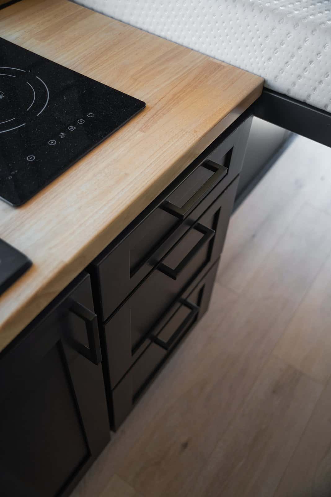 Close-up of the two-burner induction cooktop set into a light wood counter above black drawers