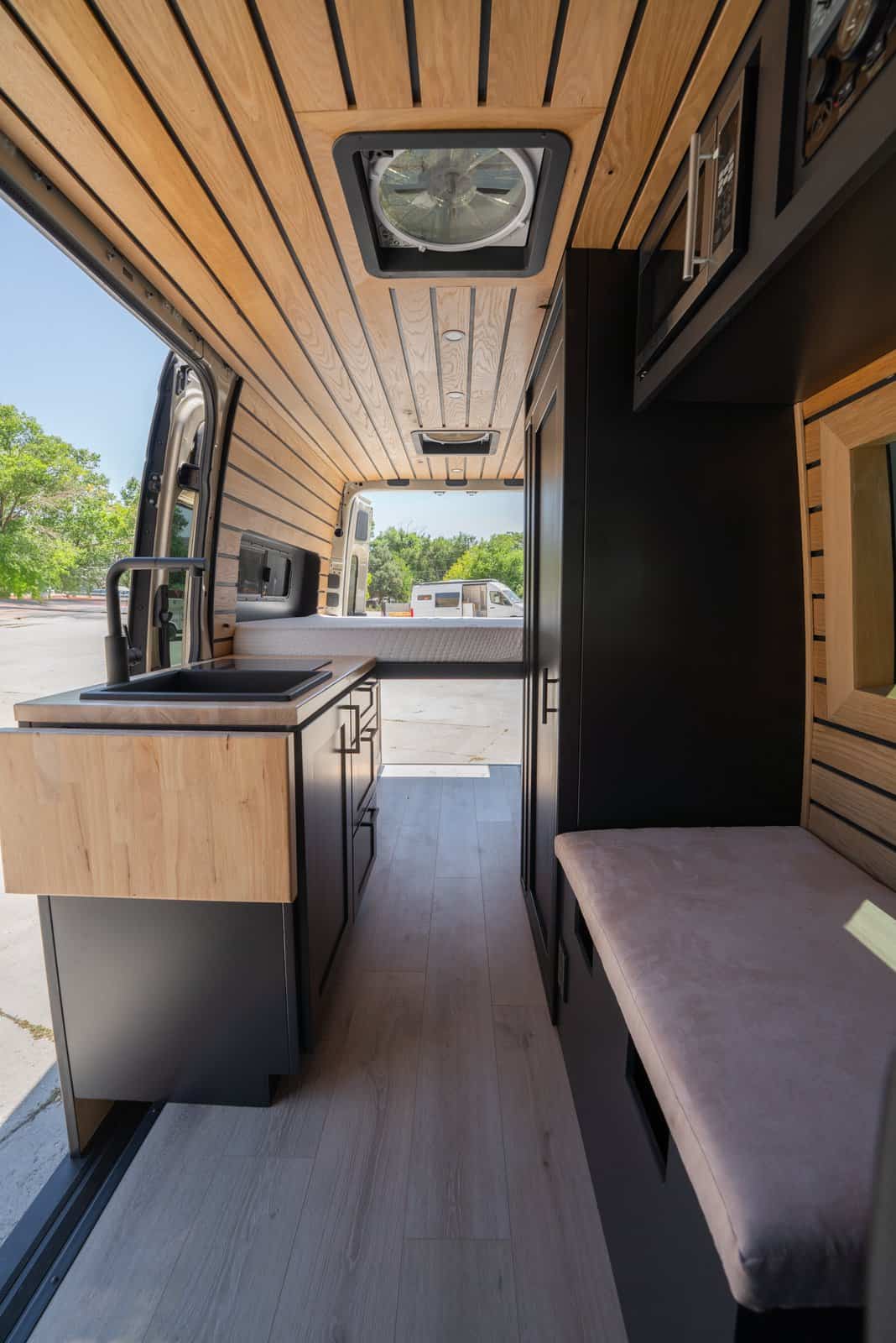 Narrow aisle between the galley counter and bench seat leading to the rear bed, with a roof fan overhead
