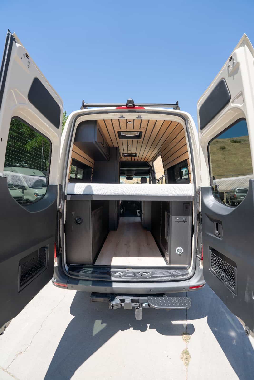 Sprinter van with both rear doors open, showing the bed platform above a storage garage
