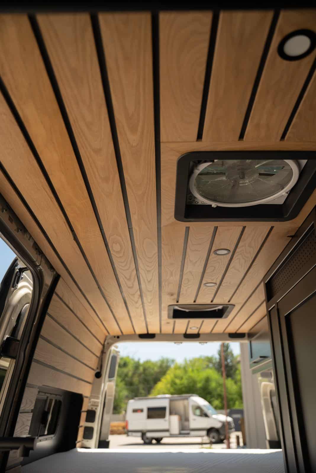 Wood slat ceiling with a roof fan and recessed lights, looking toward the open rear doors