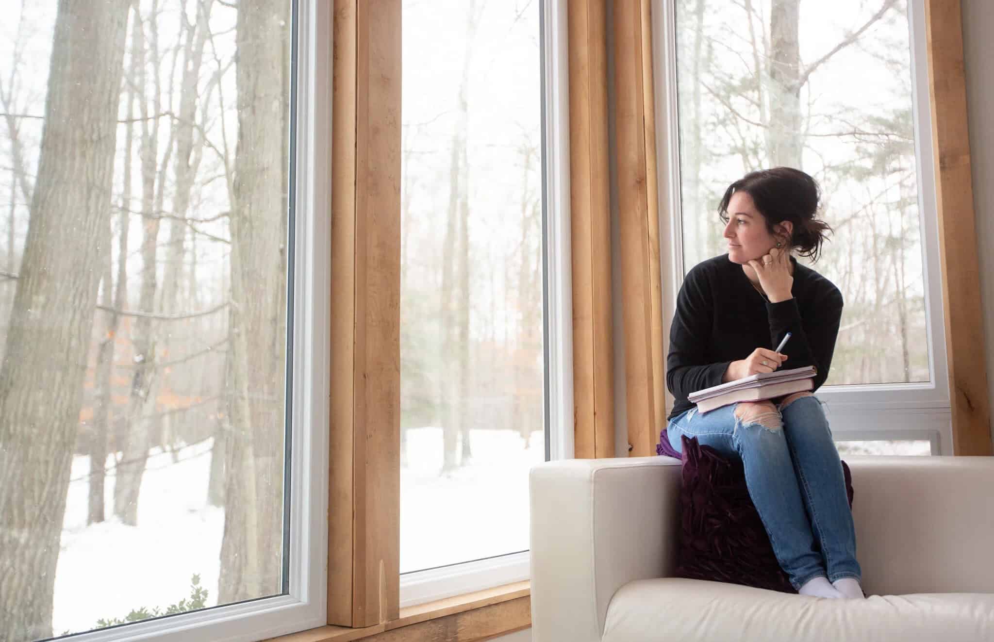 Looking out Adler Cabin’s tall wood-framed windows to a snowy forest