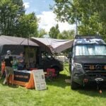 Dark camo Sprinter at the Infinity Vans booth on the grass at Adventure Van Expo, North Lake Tahoe