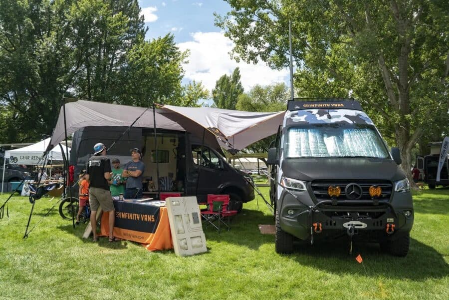 Dark camo Sprinter at the Infinity Vans booth on the grass at Adventure Van Expo, North Lake Tahoe