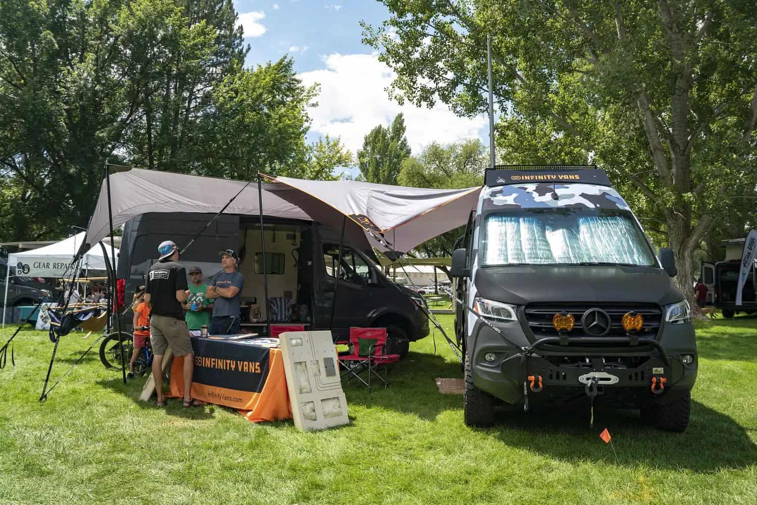 Dark camo Sprinter at the Infinity Vans booth on the grass at Adventure Van Expo, North Lake Tahoe