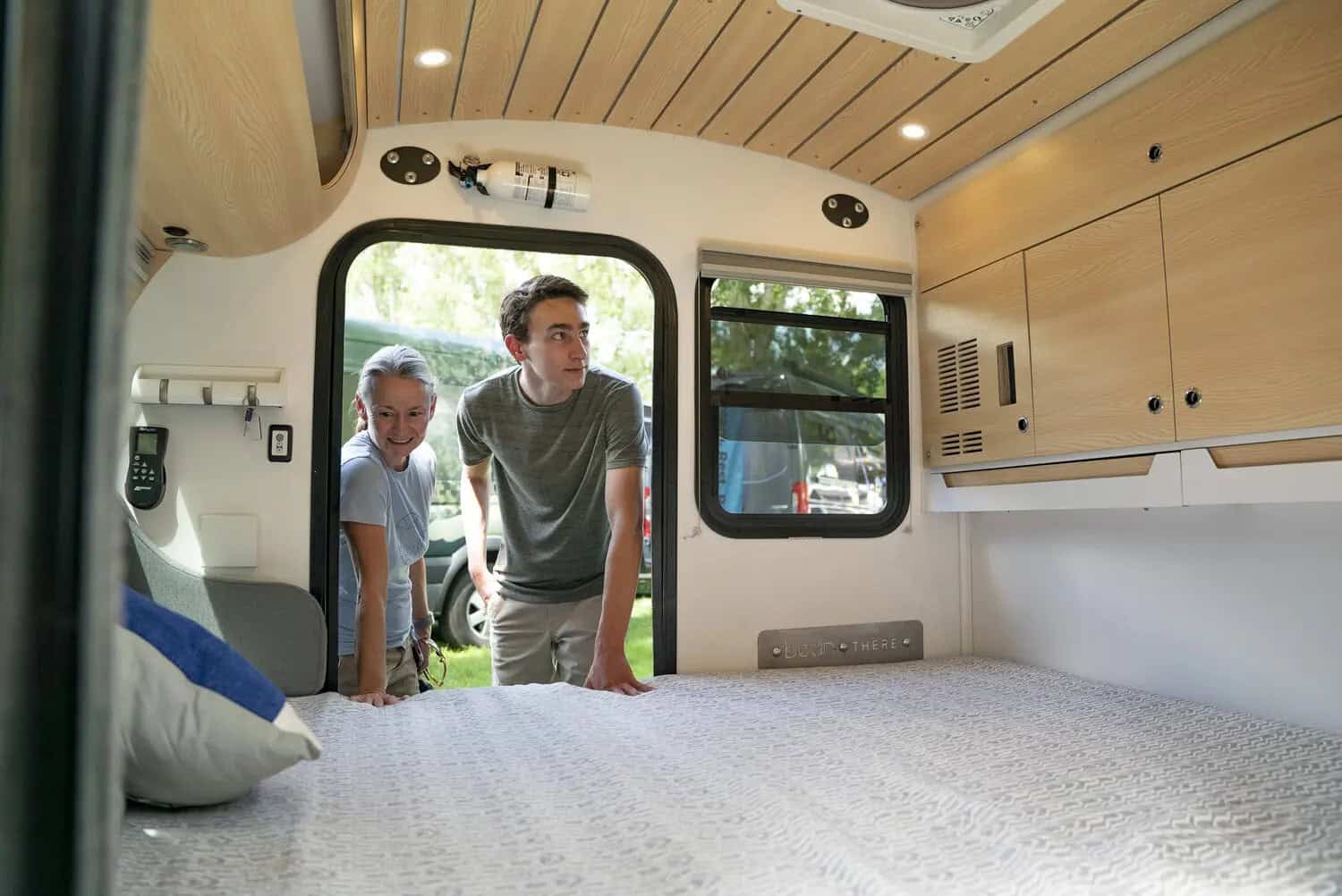 Two visitors looking into a light-wood camper-van interior at Adventure Van Expo, North Lake Tahoe