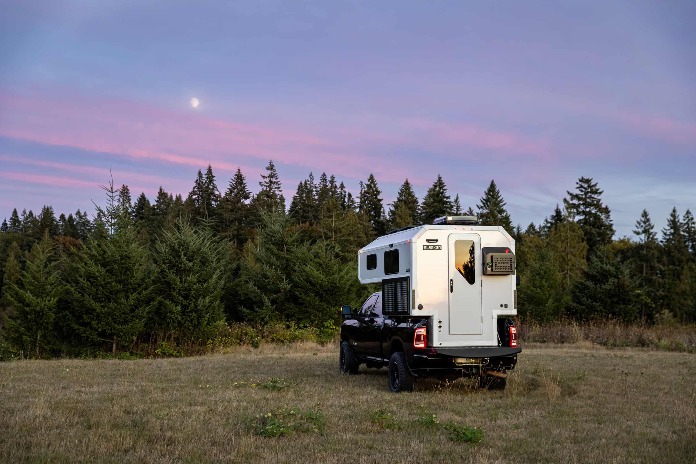 White hard-sided camper, wide rear view at sunset