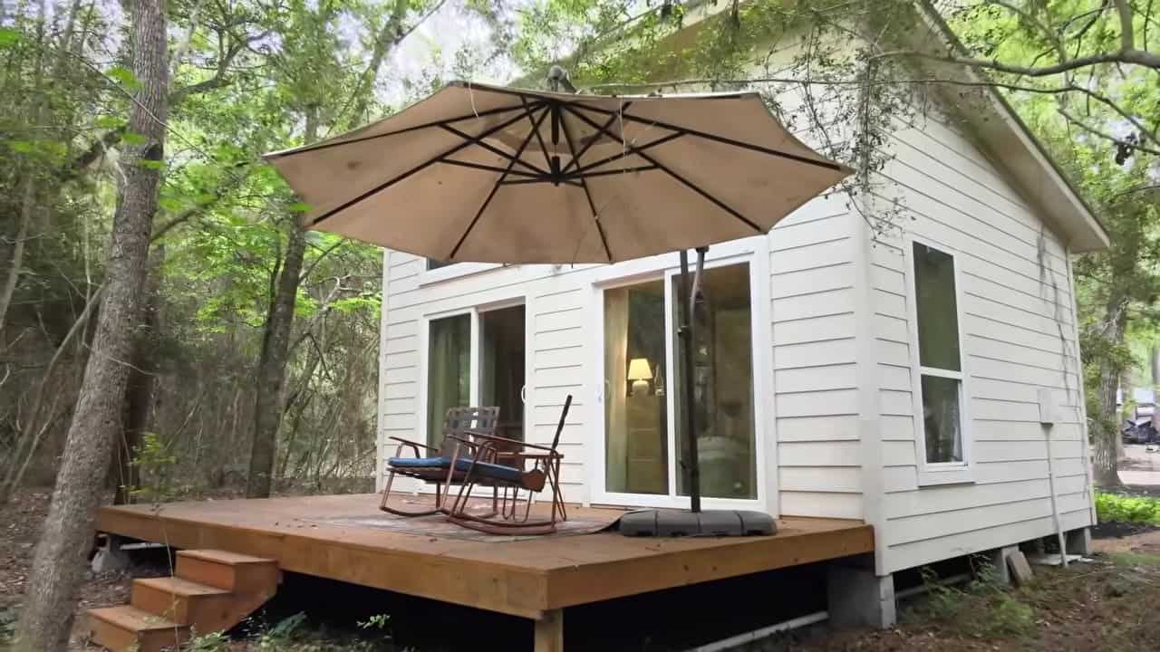 Back porch and deck of Annie’s tiny house with sliding glass doors opening to the woods